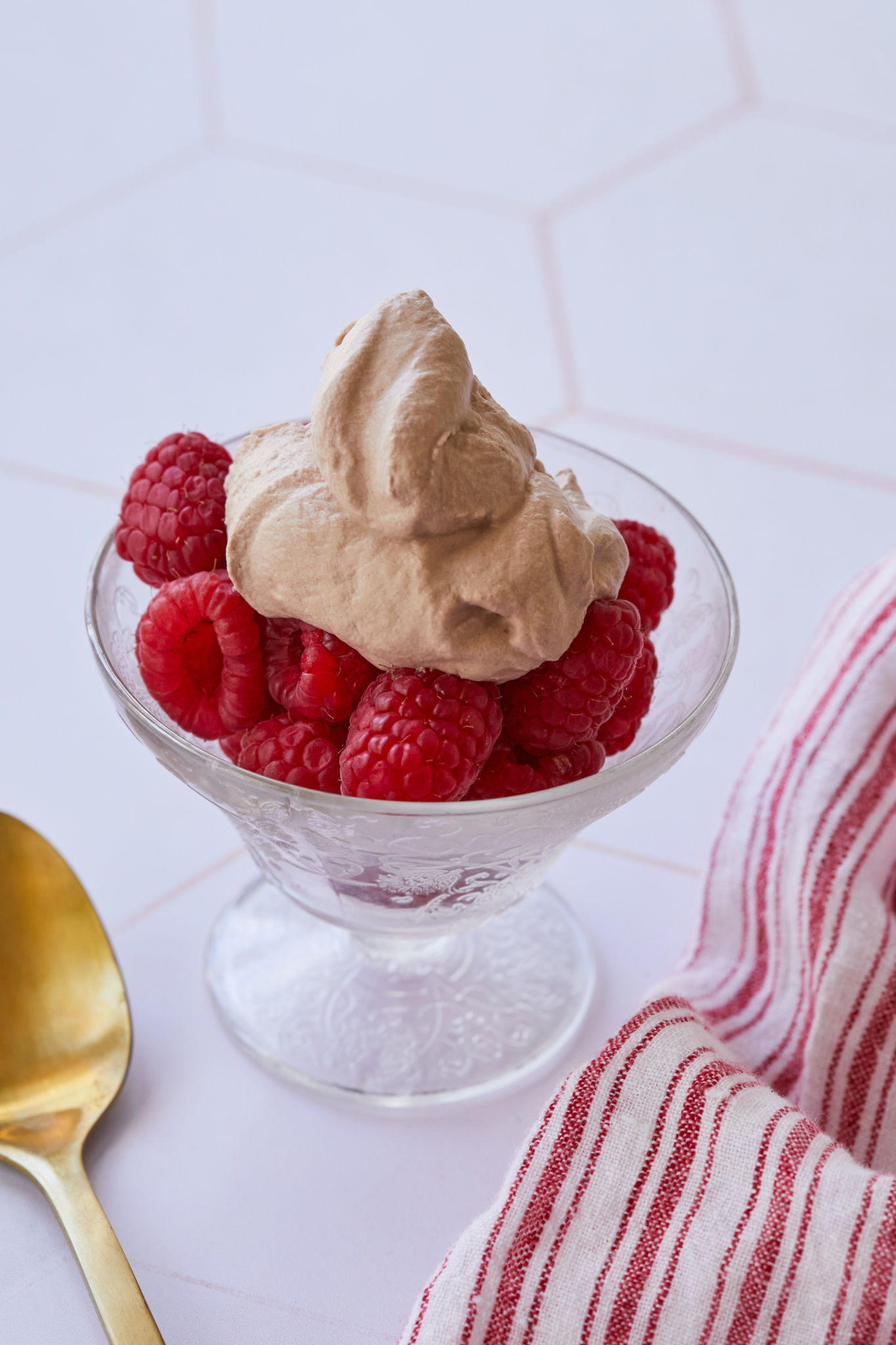 Fresh homemade chocolate whipped cream is dolloped on top a serving of raspberries. 