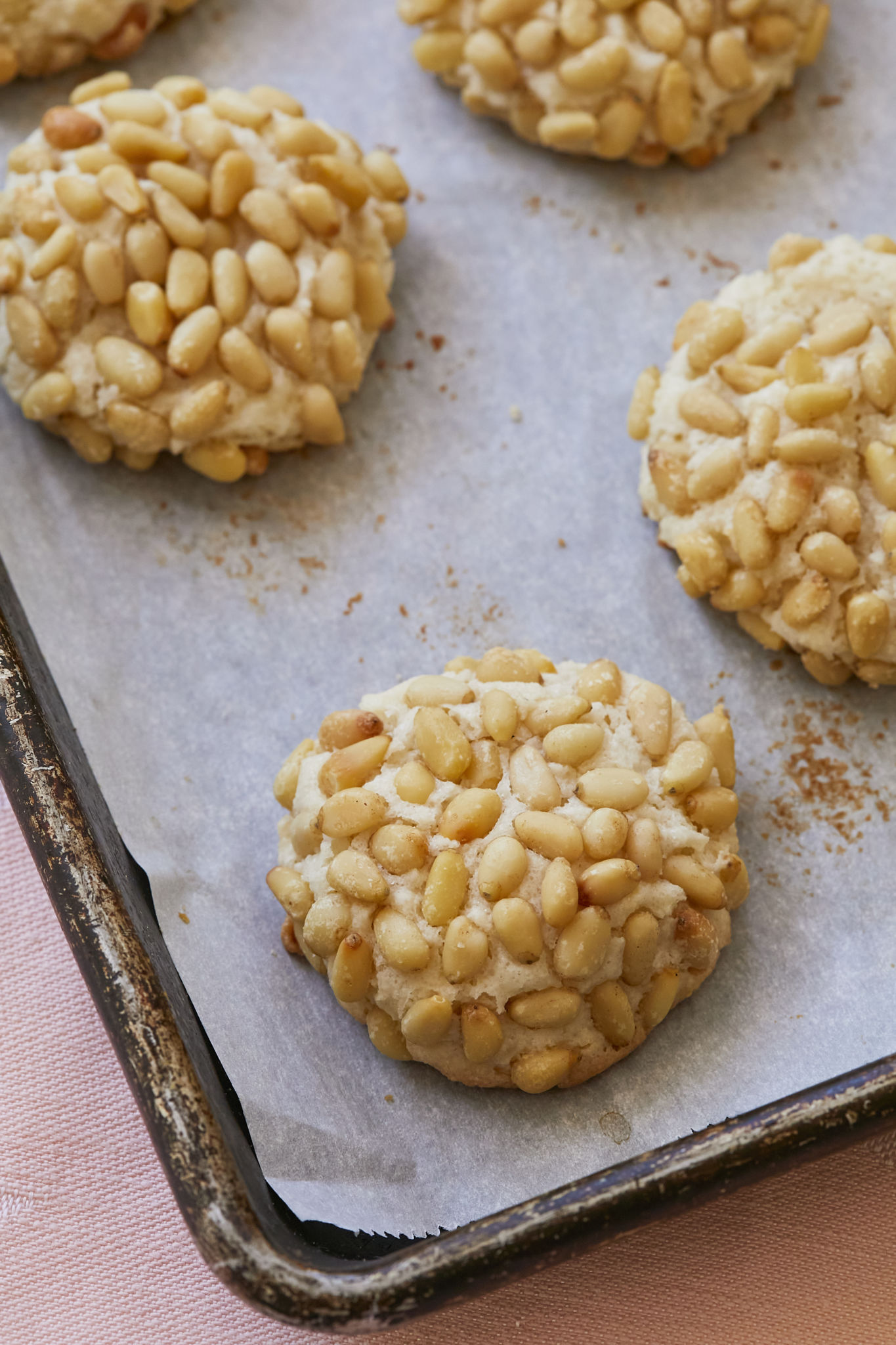 A close-up image of Italian Pignoli Cookies. The almond cookies are covered in toasted pine nuts.