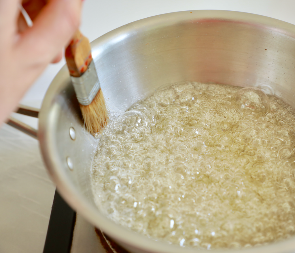 Using a brush to avoid crystallization while making caramel.