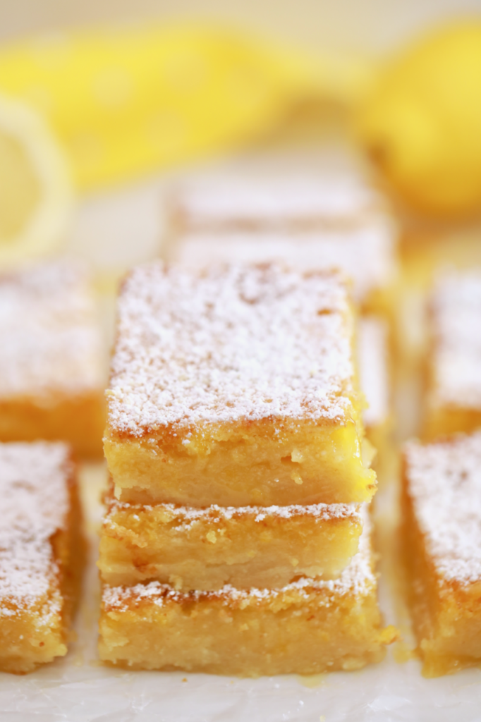 A stack of lemon bars dusted with powdered sugar and ready to eat.
